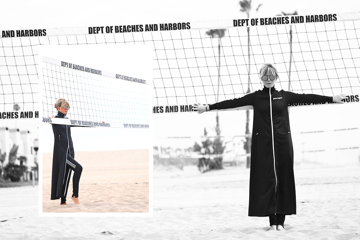 Laura dunn poses in palm angels athleisure full body duster in black in Santa Monica beach on a cloudy day